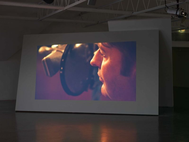 A film still showing a close-up of a typewriter, projected on a freestanding wall