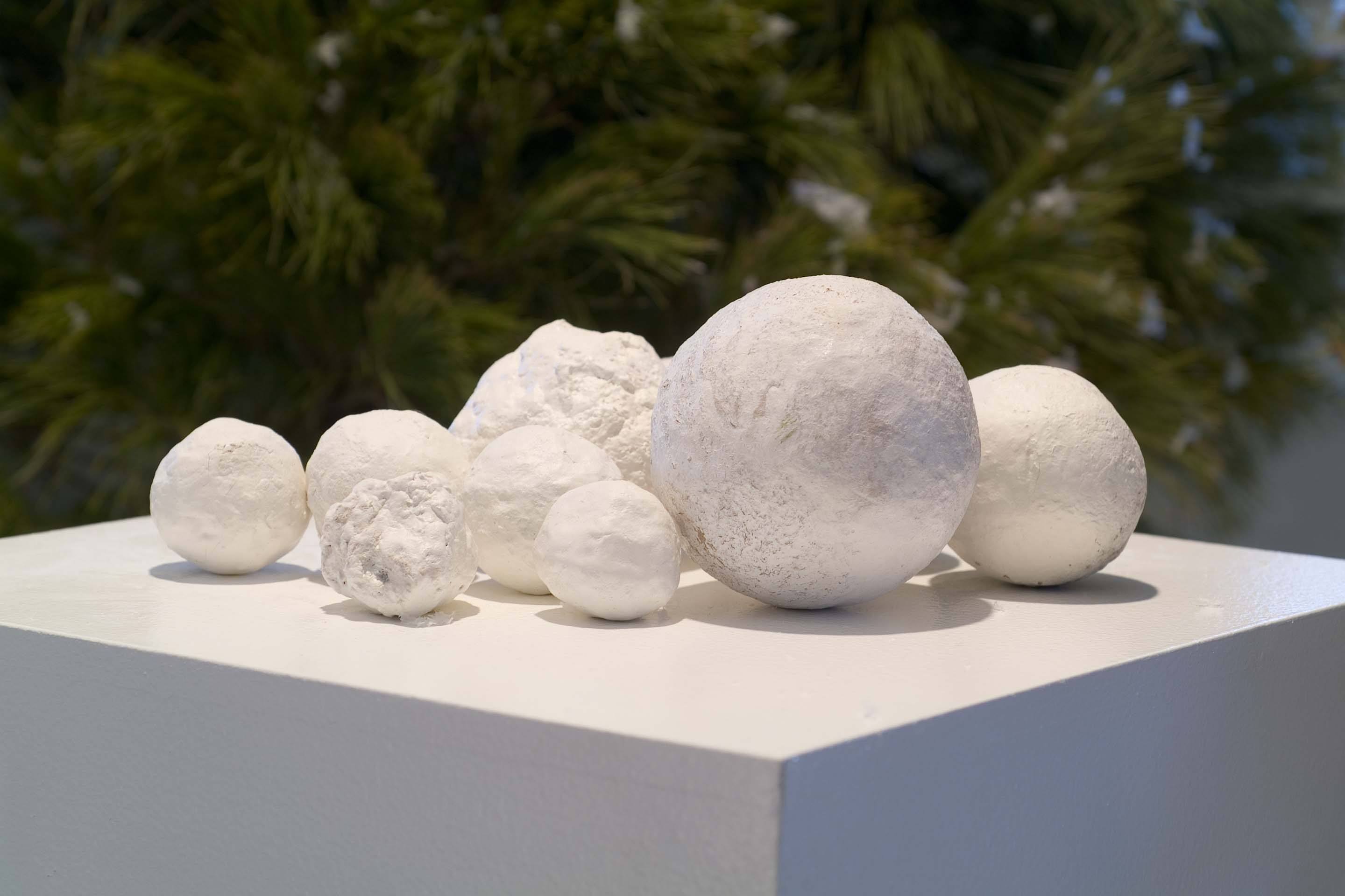 White spheres of papier-mache rest atop a square platform.