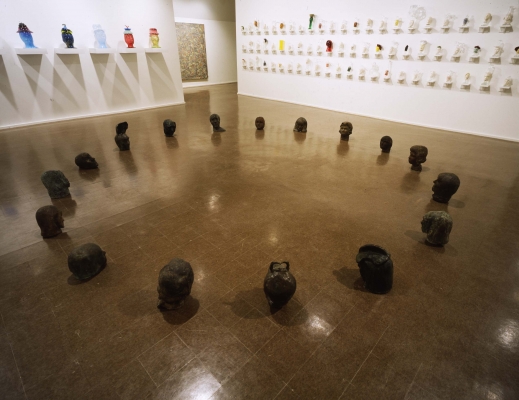 Bronze busts of human heads face each other in a large circle on the floor.