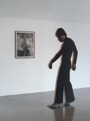 A wooden silhouette, in a walking pose, in front of a print