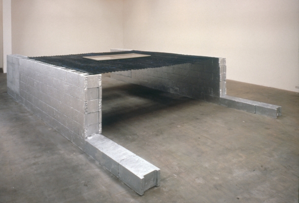 Two lines of concrete blocks rest on the floor, bearing a sheet of steel painted black with two 'feet' of blocks sticking out